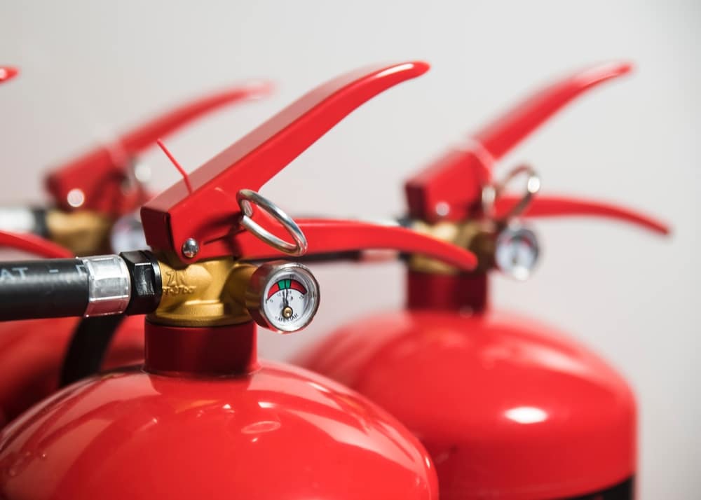 Close-up of red fire extinguishers with pressure gauges, highlighting safety equipment in focus against a neutral background.